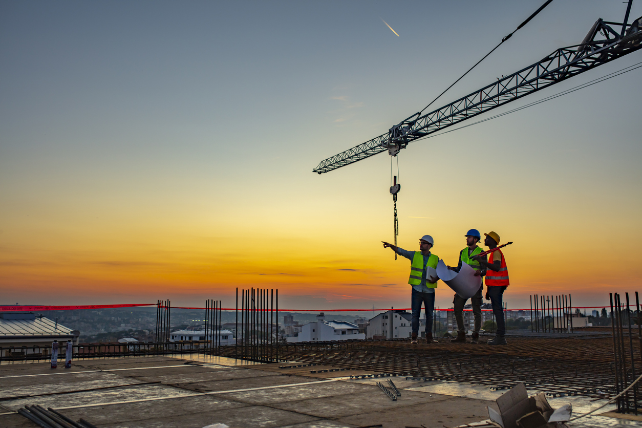 Multi ethic workers talking at construction site reviewing plans Close-up of engineer using tablet near oil refinery.